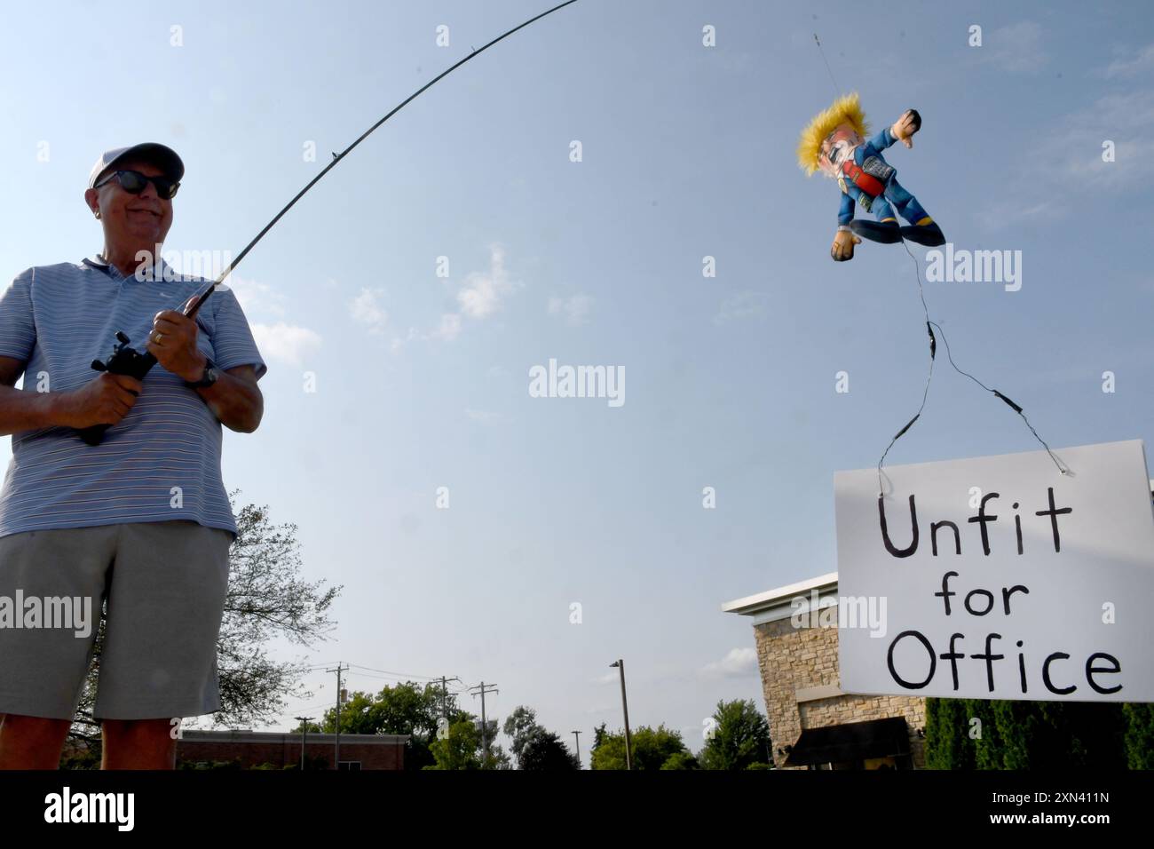 Mount Pleasant, Wisconsin, USA. 30th July, 2024. BILL APPMAN holds a Donald Trump puppet at the end of a fishing rod with a sign declaring Trump 'Unfit for Office' on one side Mount Pleasant, Wisconsin, USA. 30th July, 2024. BILL APPMAN holds a Donald Trump puppet at the end of a fishing rod with a sign declaring Trump 'Unfit for Office' on one side