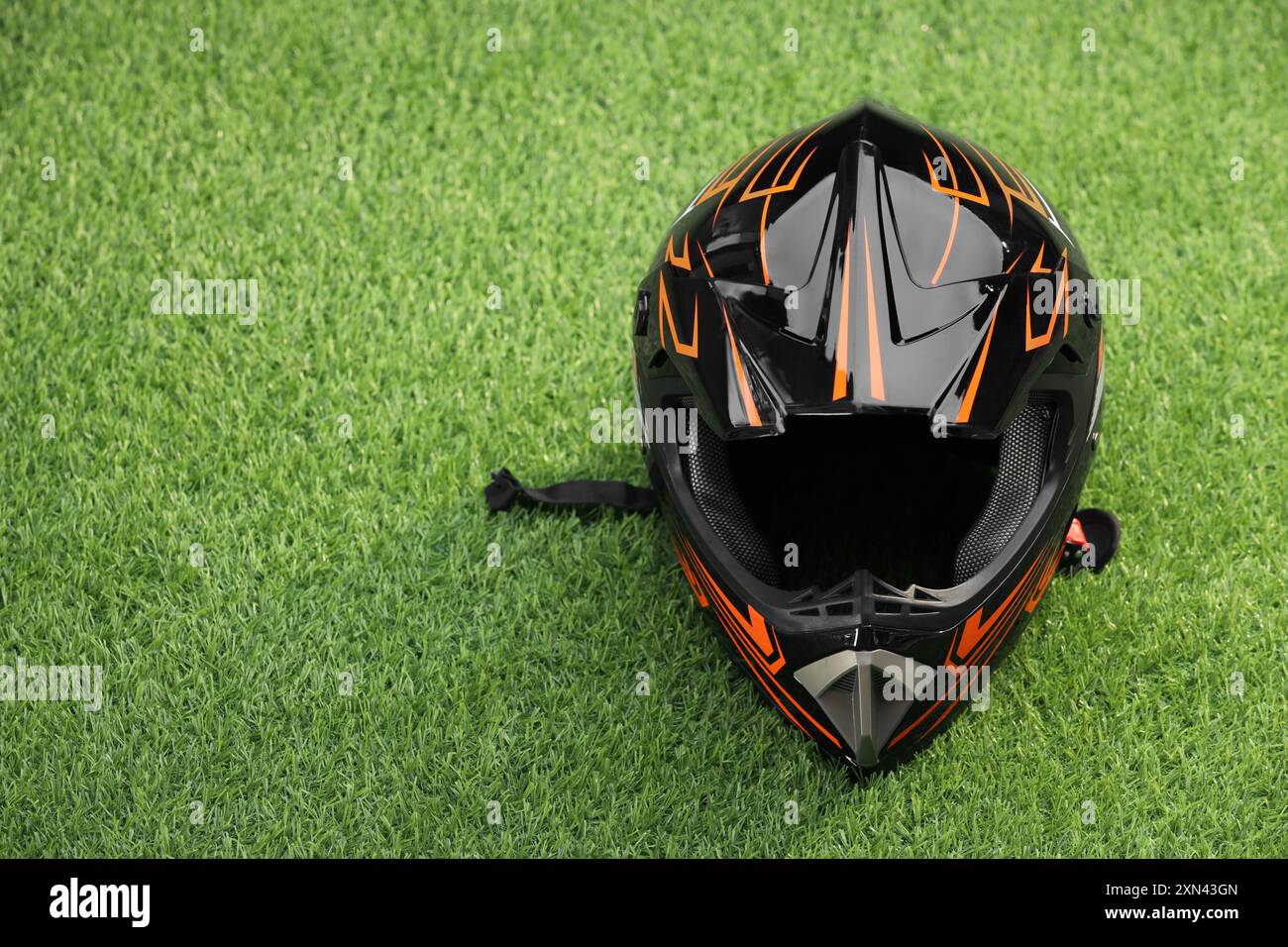 Modern motorcycle helmet with visor on green grass, space for text ...