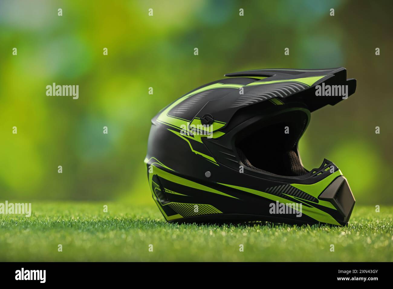 Modern motorcycle helmet with visor on green grass, space for text ...