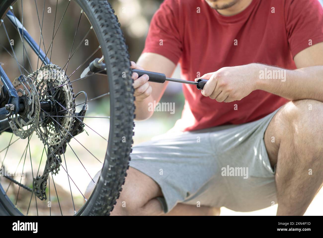 Man pumping up a bike tire using small hand pump young man inflating a bicycle tire with a small pump close up Stock Photo Alamy