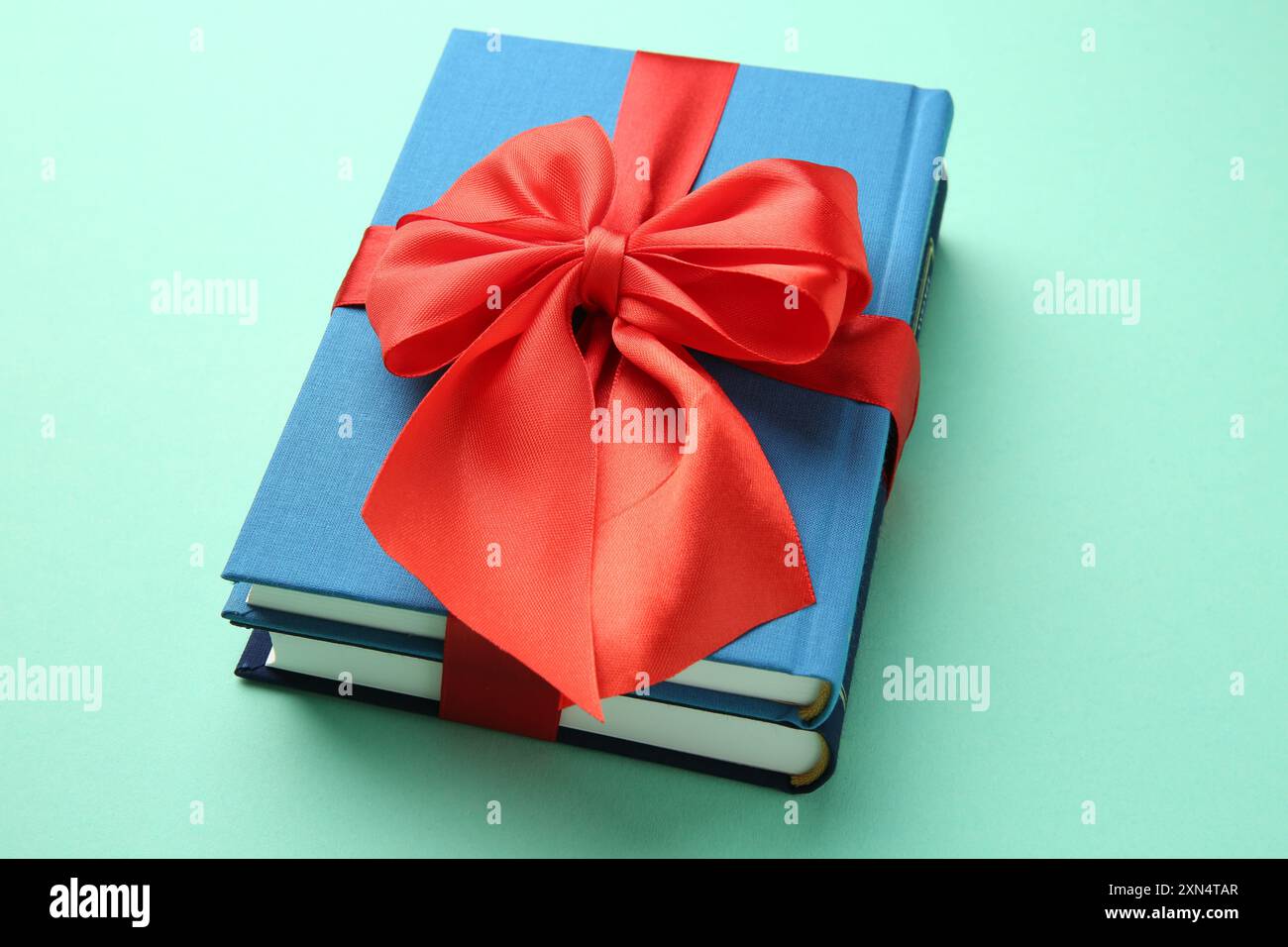 Books tied with red ribbon on turquoise background Stock Photo - Alamy