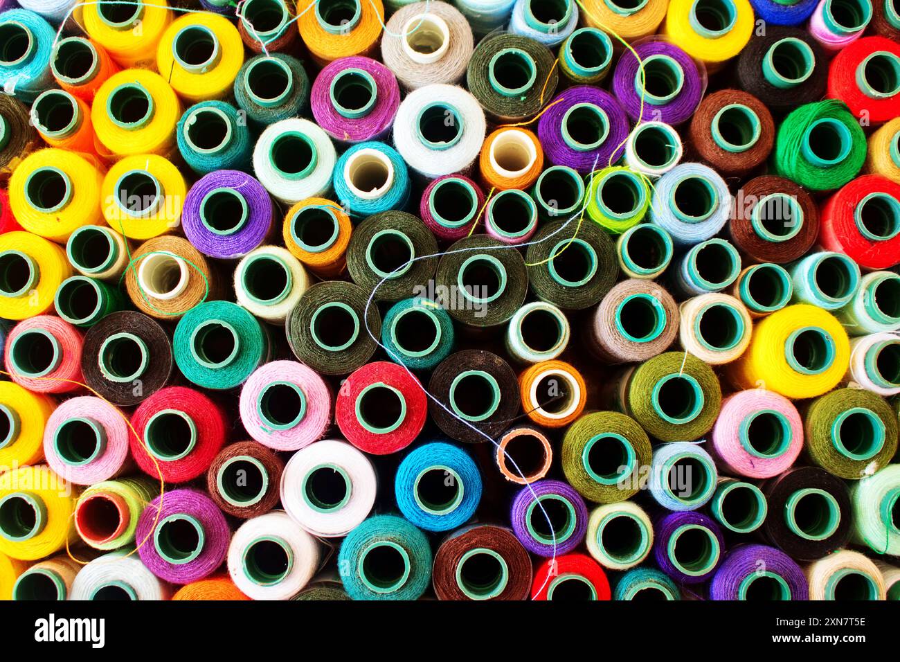Top view of a vibrant collection of various colored thread spools. Multicolor sewing threads on reels. Colorful rolls of thread for sewing. Colorful a Stock Photo
