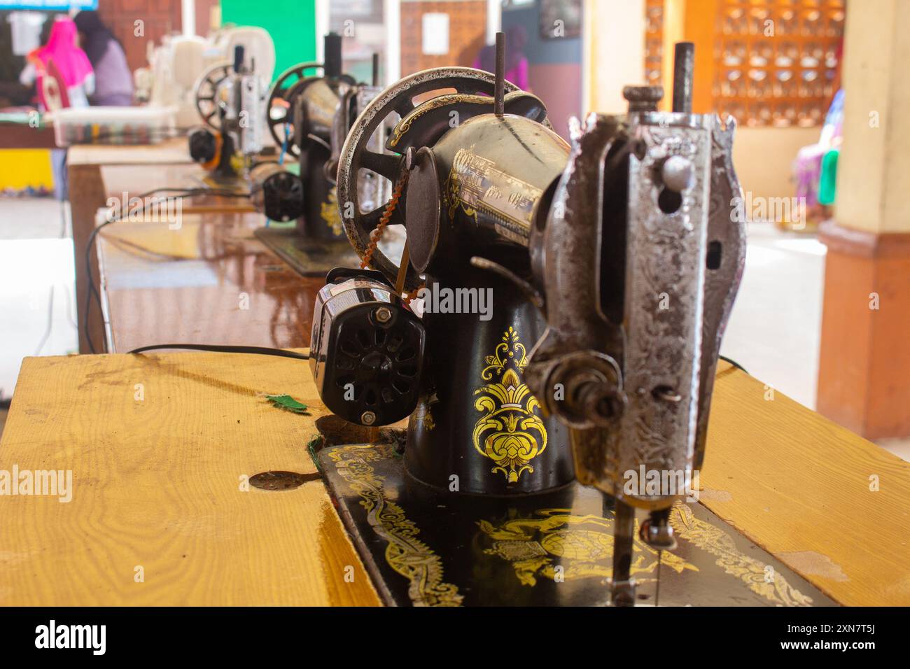 Row of antique sewing machines showcased on a wooden table with selective focus Stock Photo