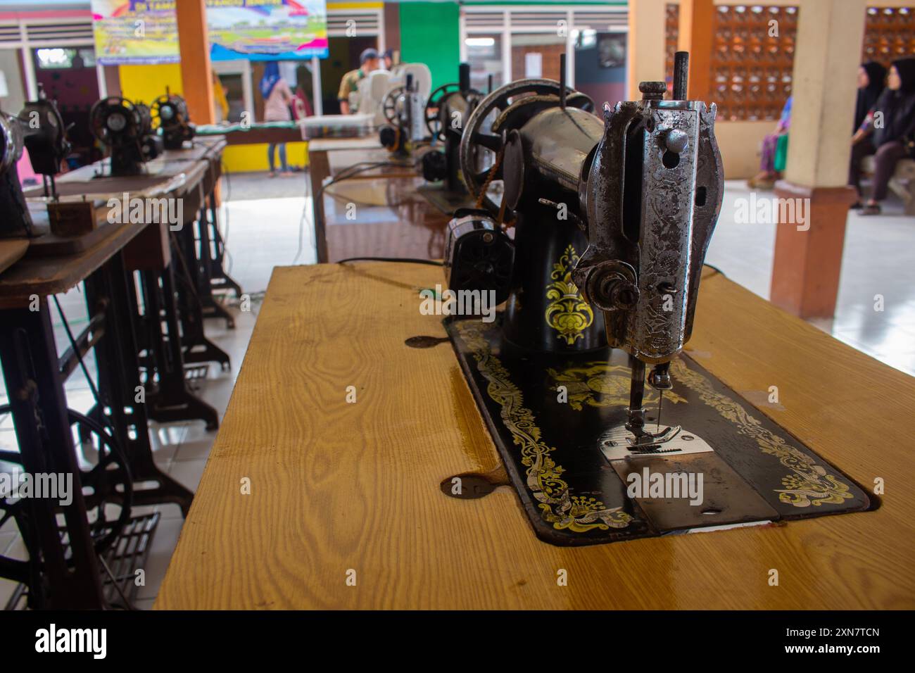 Row of antique sewing machines showcased on a wooden table with selective focus Stock Photo