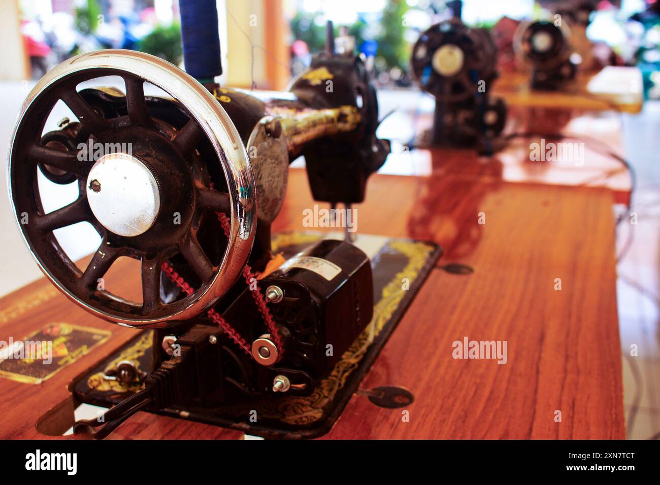 Row of antique sewing machines showcased on a wooden table with selective focus Stock Photo