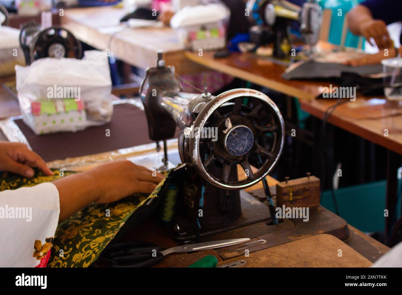 Row of antique sewing machines showcased on a wooden table with selective focus Stock Photo