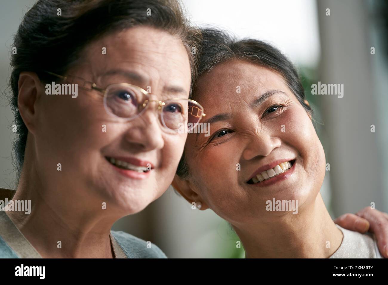portrait of two senior asian woman sitting on couch at home happy and smiling Stock Photo