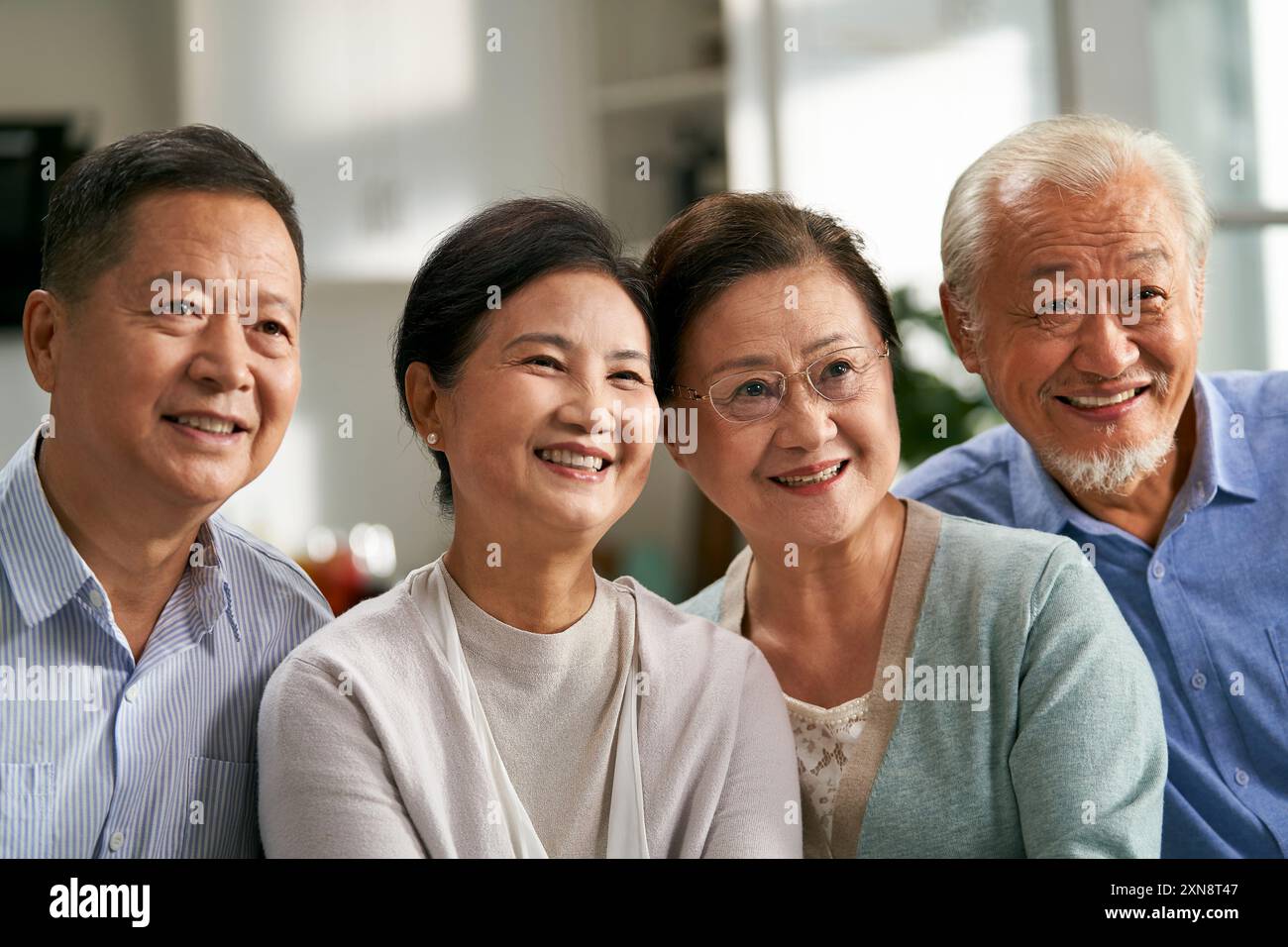 group of happy senior asian people sitting on couch at home watching tv together Stock Photo