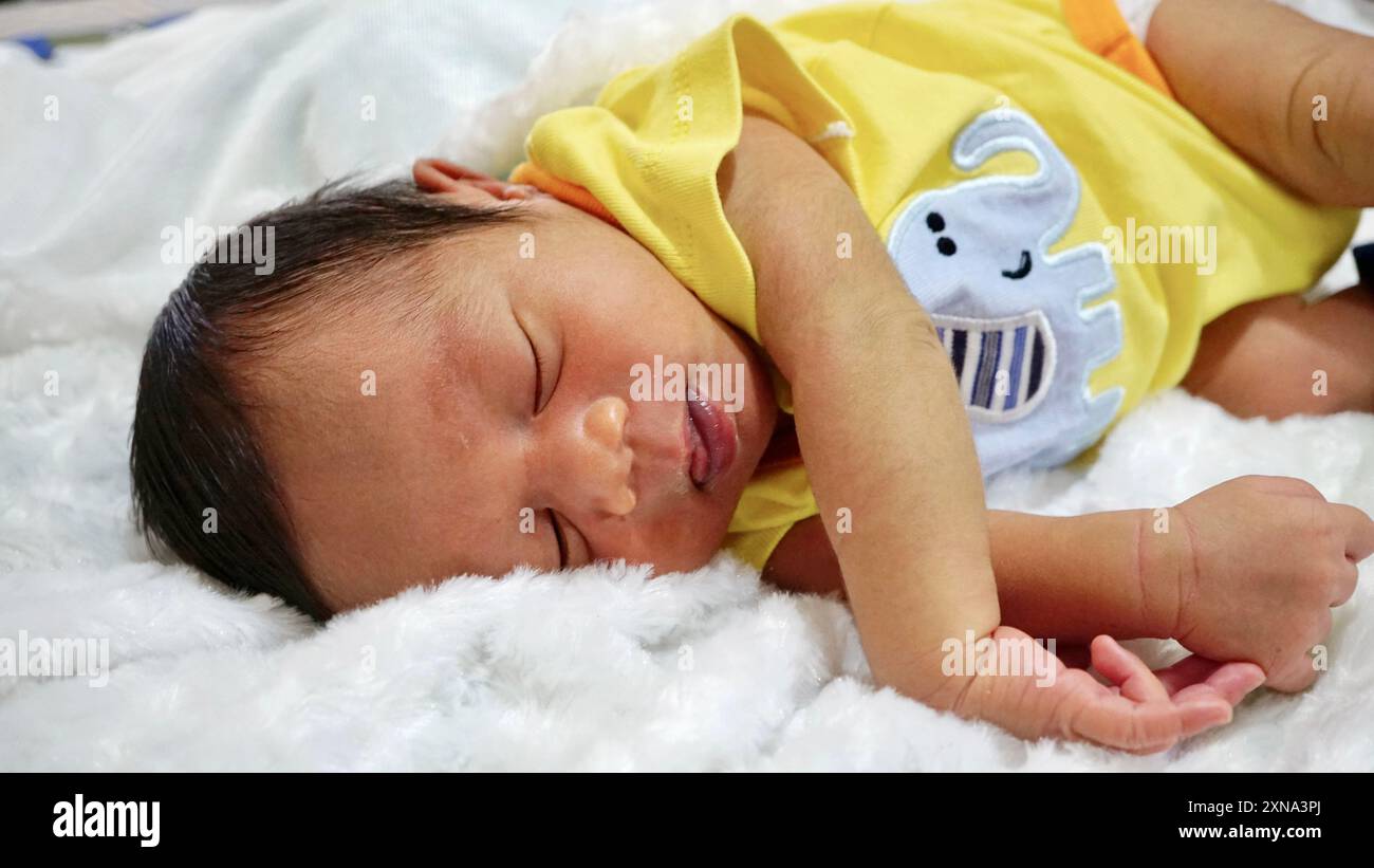 newborn baby boy wearing yellow clothes sleeping on a soft mattress Stock Photo Alamy