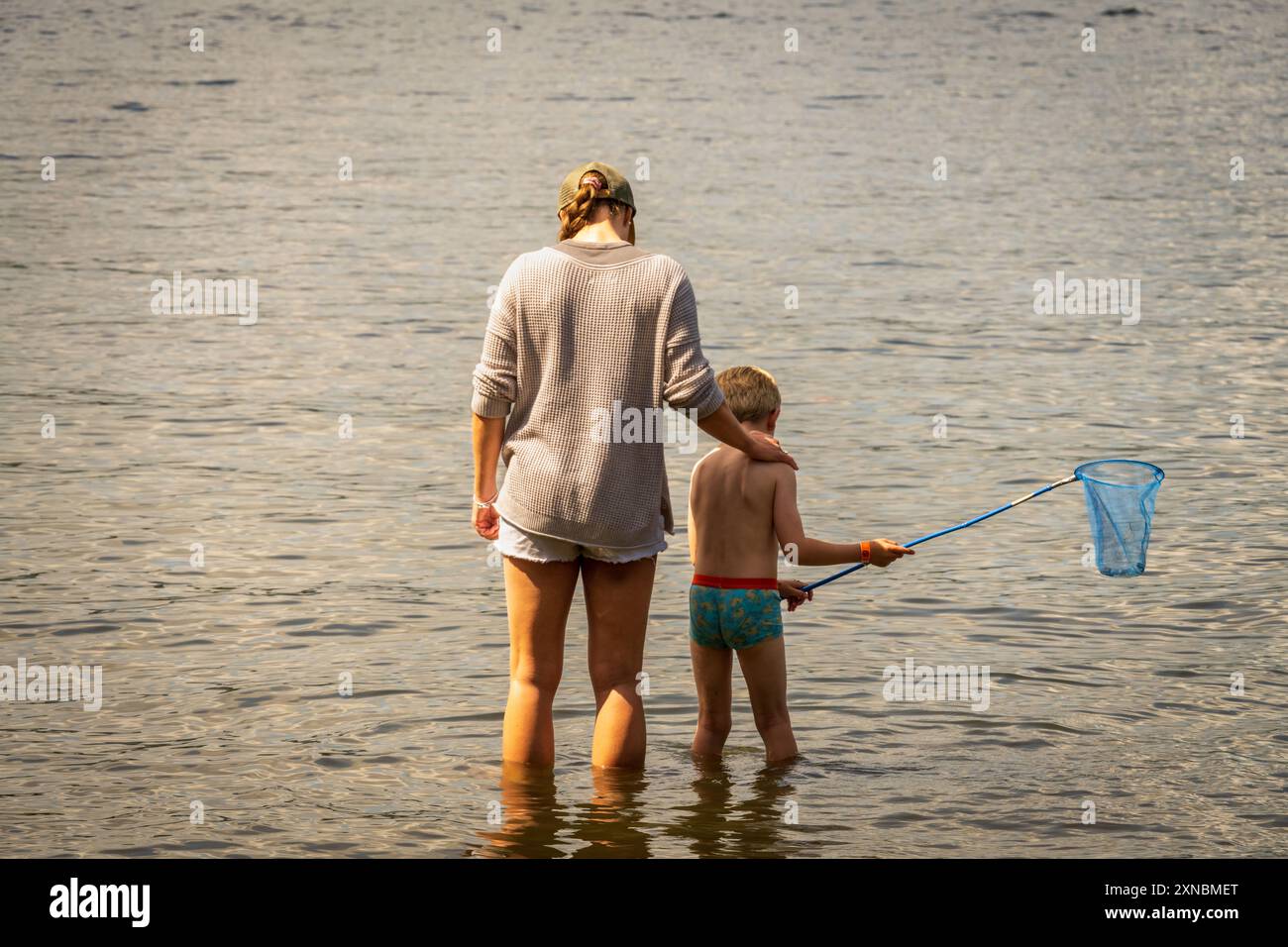 Summer holiday woman and boy paddling with fishing net. Stock Photo