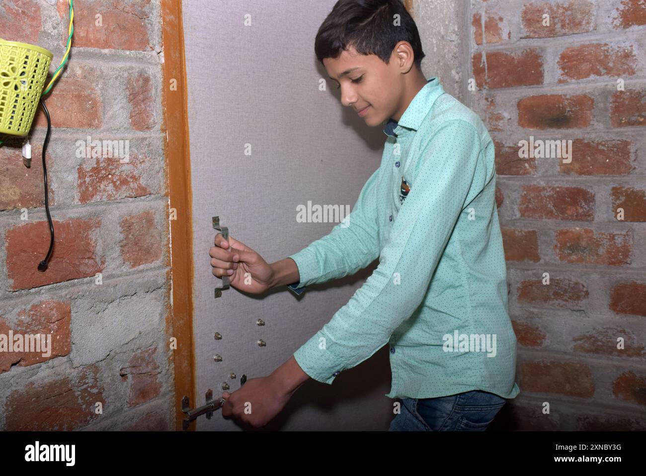 Teenage Indian boy slamming door, wearing a light green shirt with black dots Stock Photo