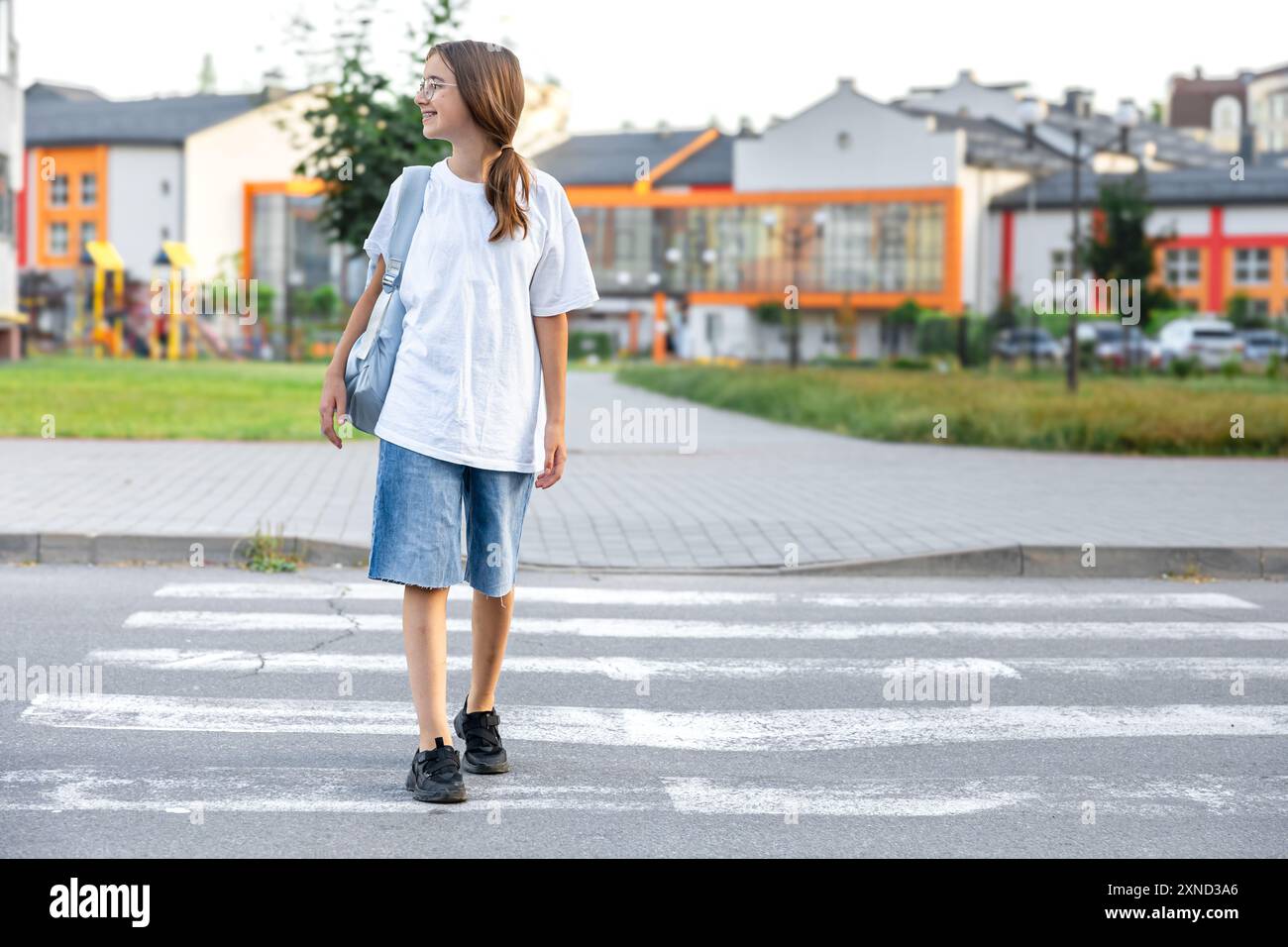 The girl goes to school. A schoolgirl crosses a pedestrian crossing ...