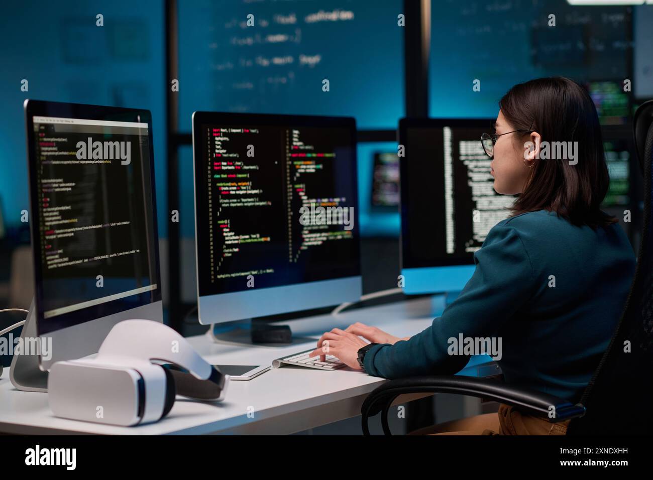 Female IT developer writing code for VR project at office workplace with focus on computer screens copy space Stock Photo
