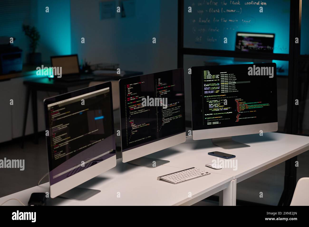 Background image of IT development office and three computer monitors on table in blue light, copy space Stock Photo
