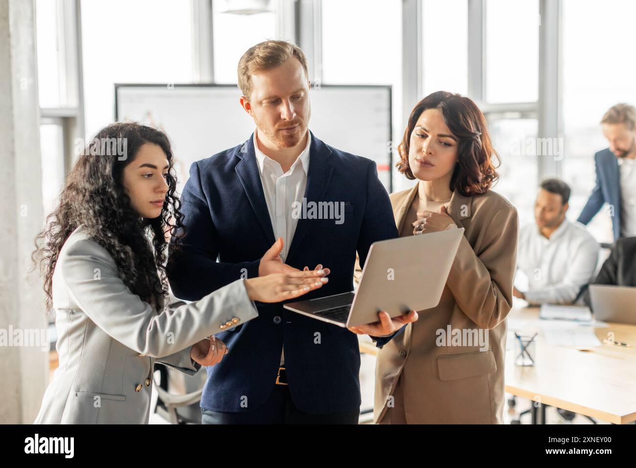 Business Professionals Discussing Project on Laptop in Modern Office Stock Photo