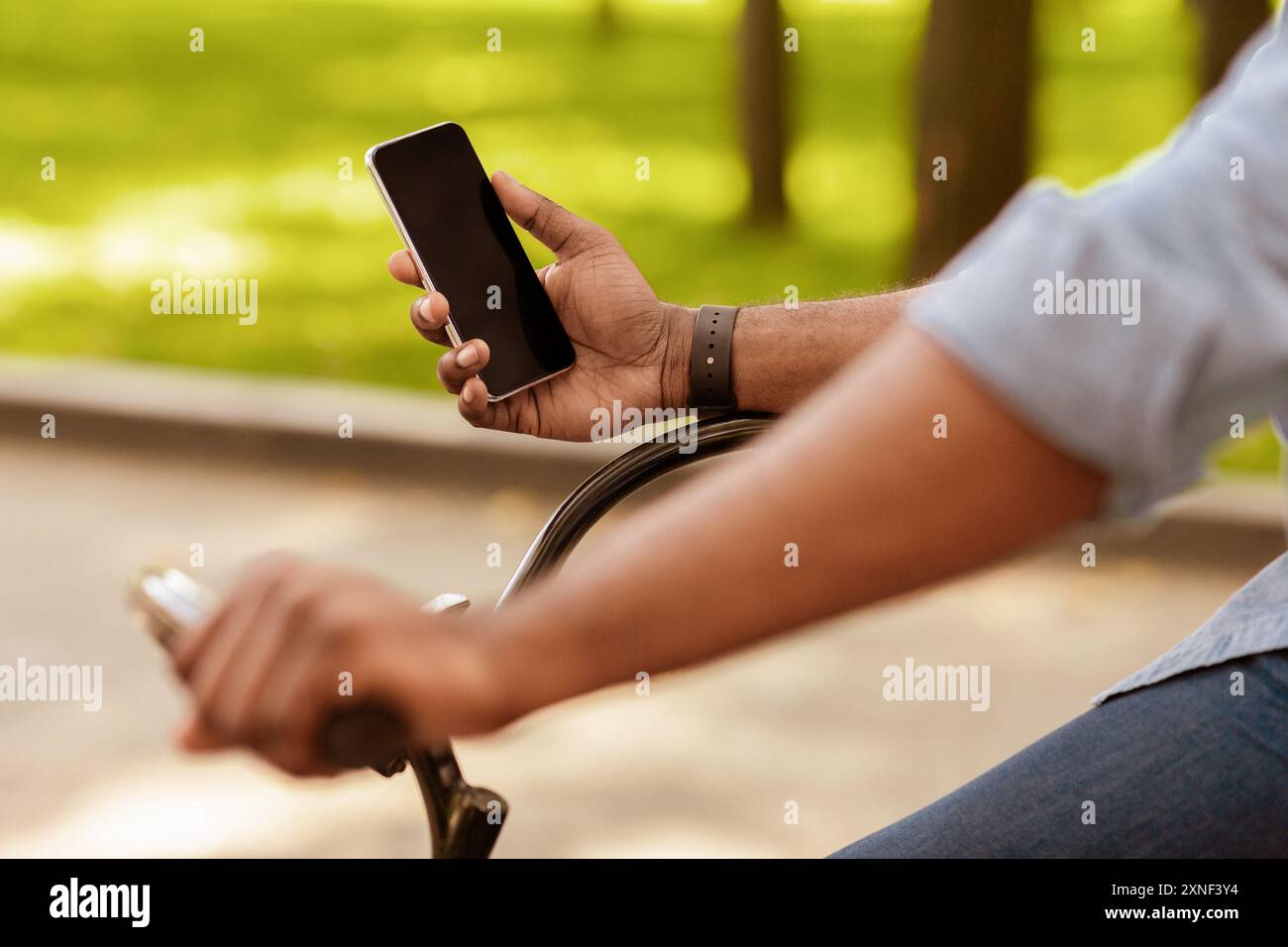 Afro man riding bike and using smartphone with black screen Stock Photo