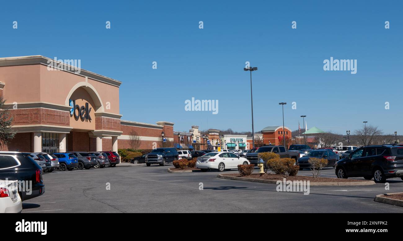 SEVIERVILLE, TN - 12 MAR 2024: Strip mall shopping center with multiple stores, buildings and busy parking lot with cars and vehicles, on a sunny day Stock Photo