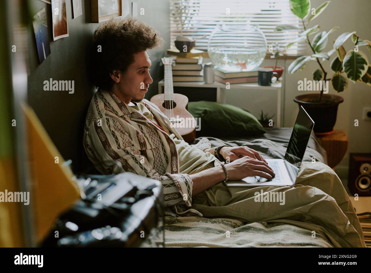 University student writing codes while chilling on soft single bed in his dorm room Stock Photo