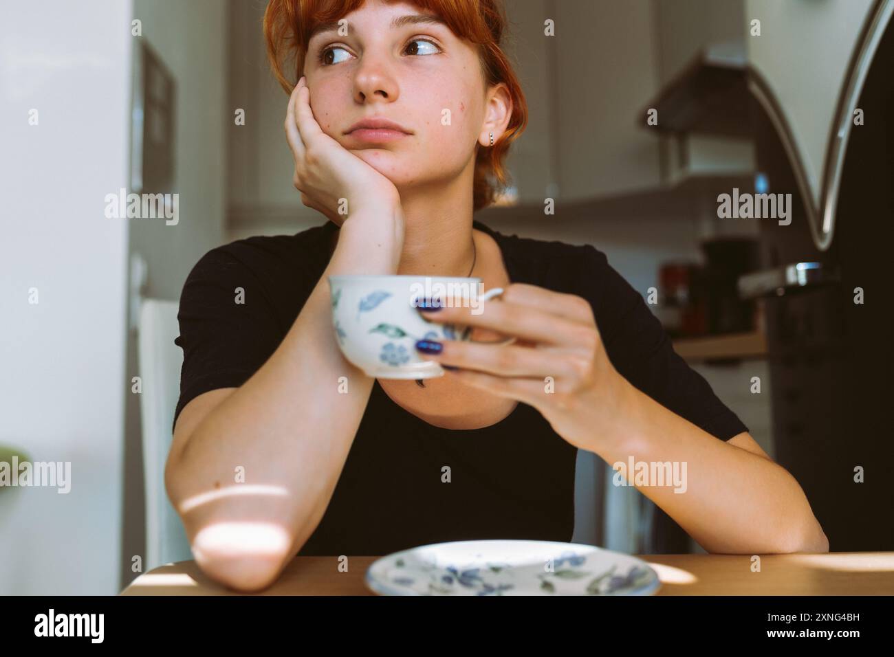 portrait young woman drinking tea or coffee in morning in kitchen Stock Photo