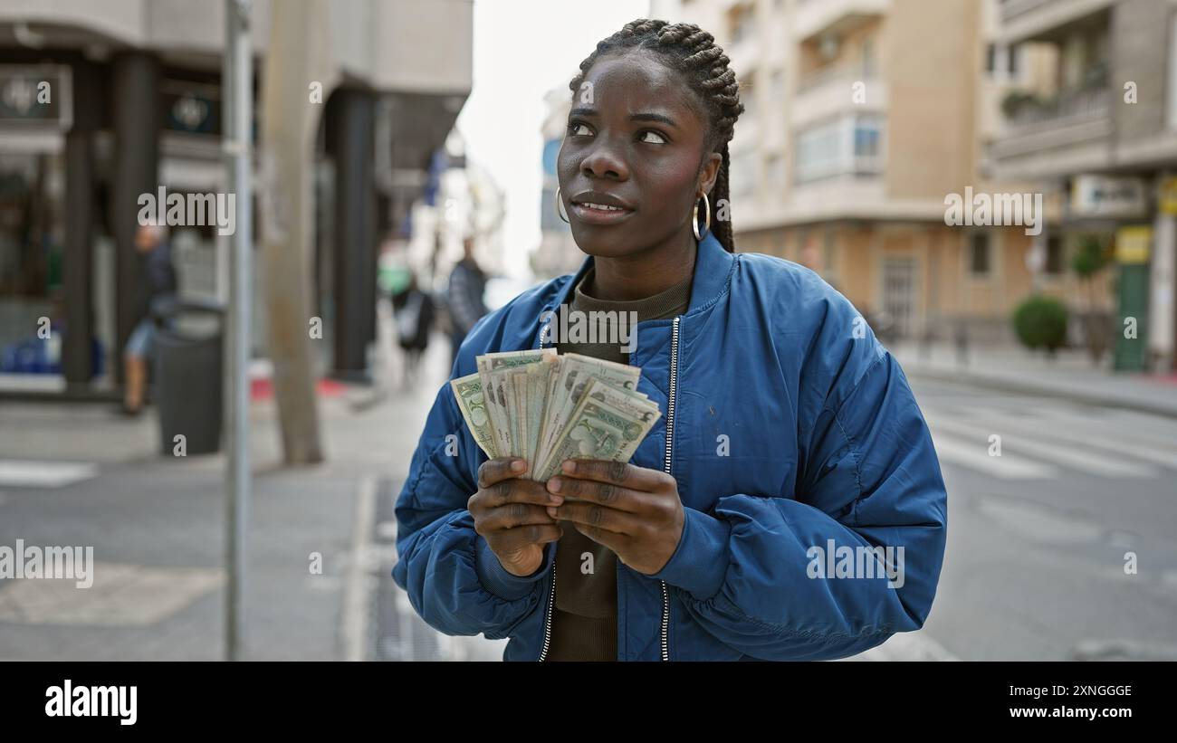 African woman with braids holding uae dirhams on a bustling city street ...