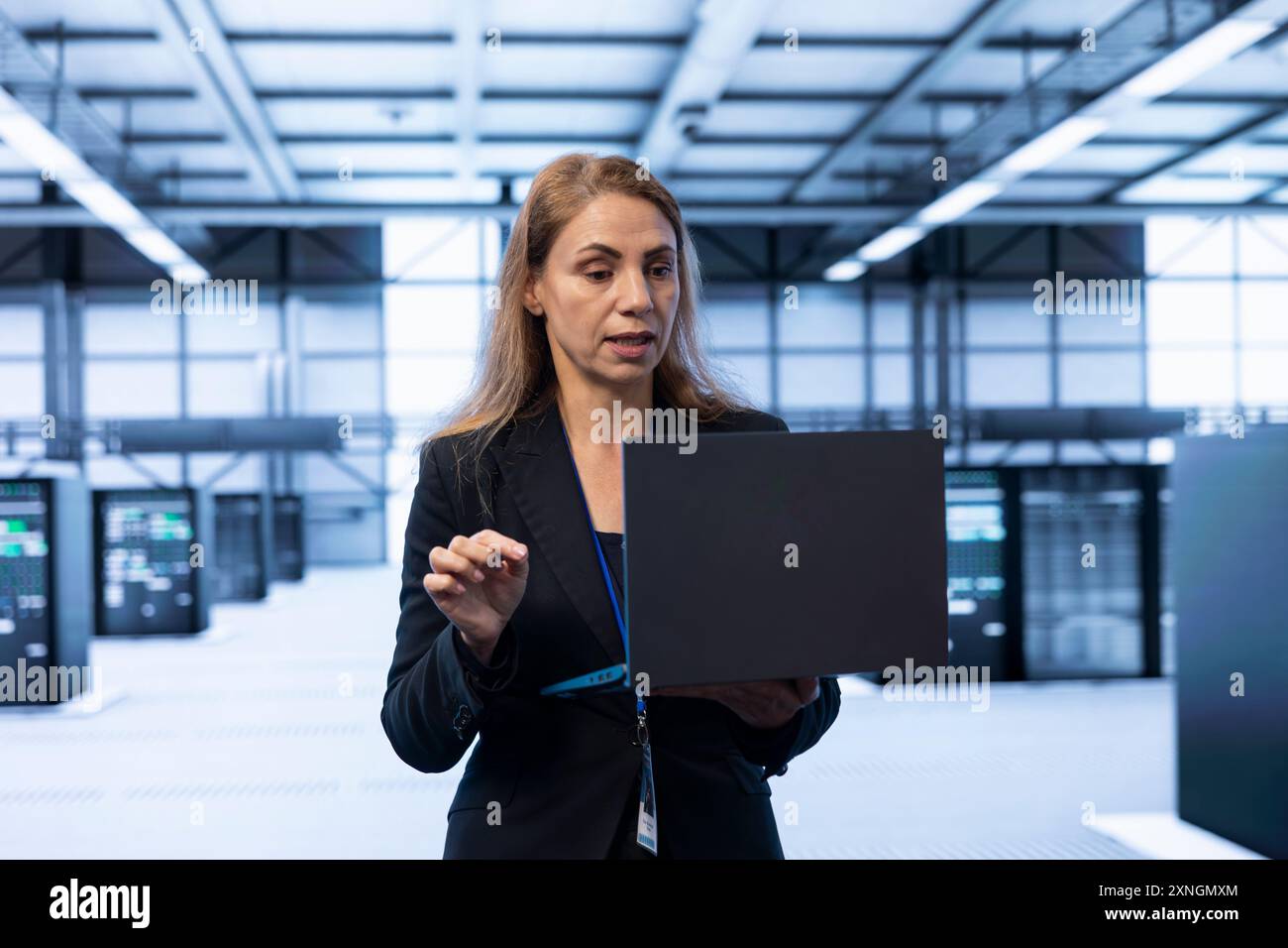 System administrator in server room using laptop to implement and maintain security measures, protecting systems from unauthorized access. Data center IT expert doing hardware upgrades using notebook Stock Photo