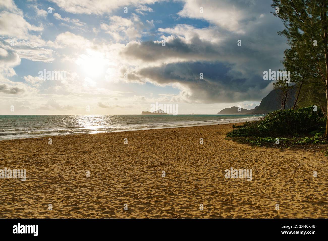 The sun shines through clouds on the beach, creating a beautiful scene ...