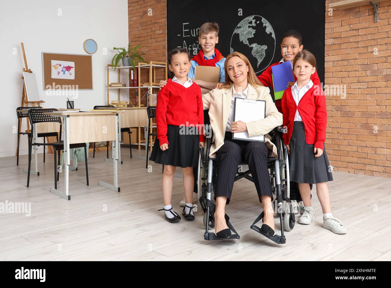 Mature Geography teacher in wheelchair with little pupils at school ...