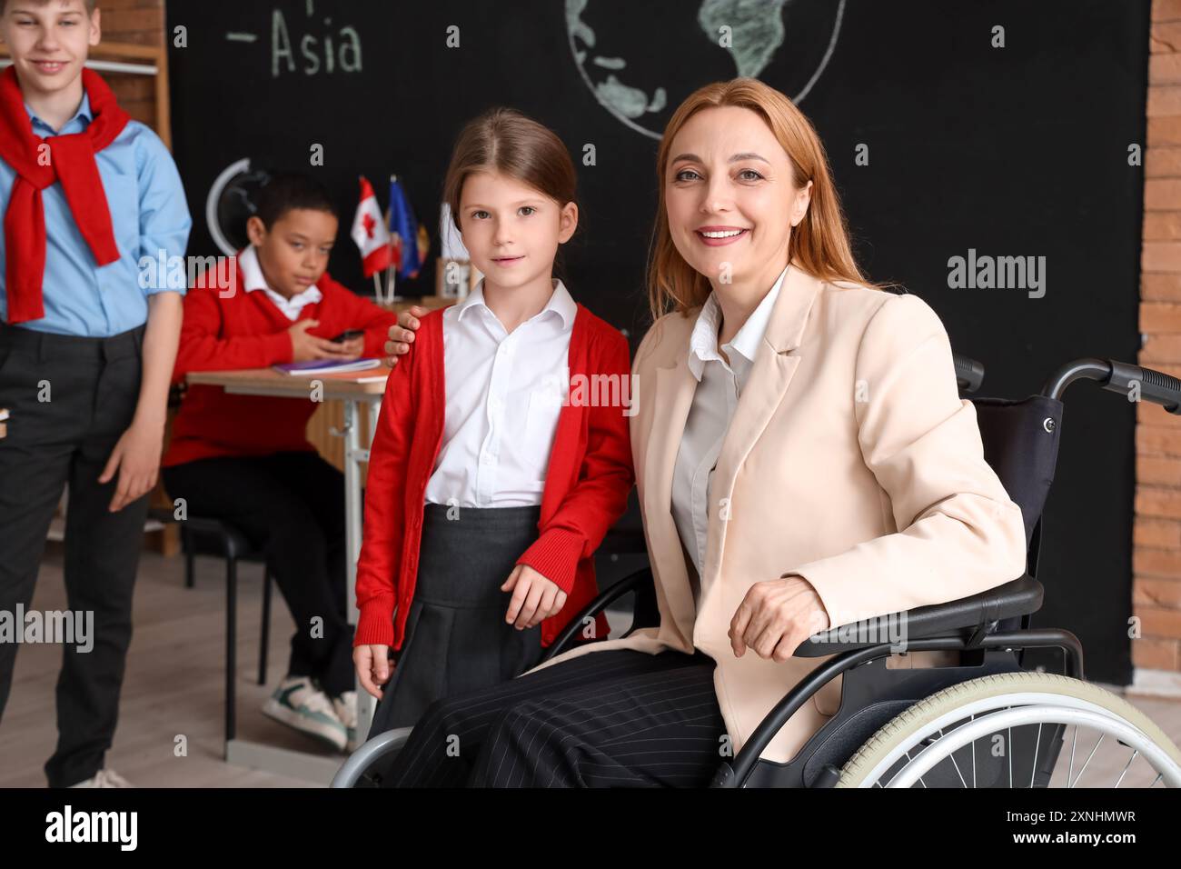 Mature Geography teacher in wheelchair hugging little girl at school ...