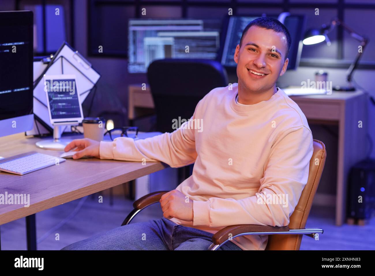 Handsome programmer working with computer in office at night Stock Photo