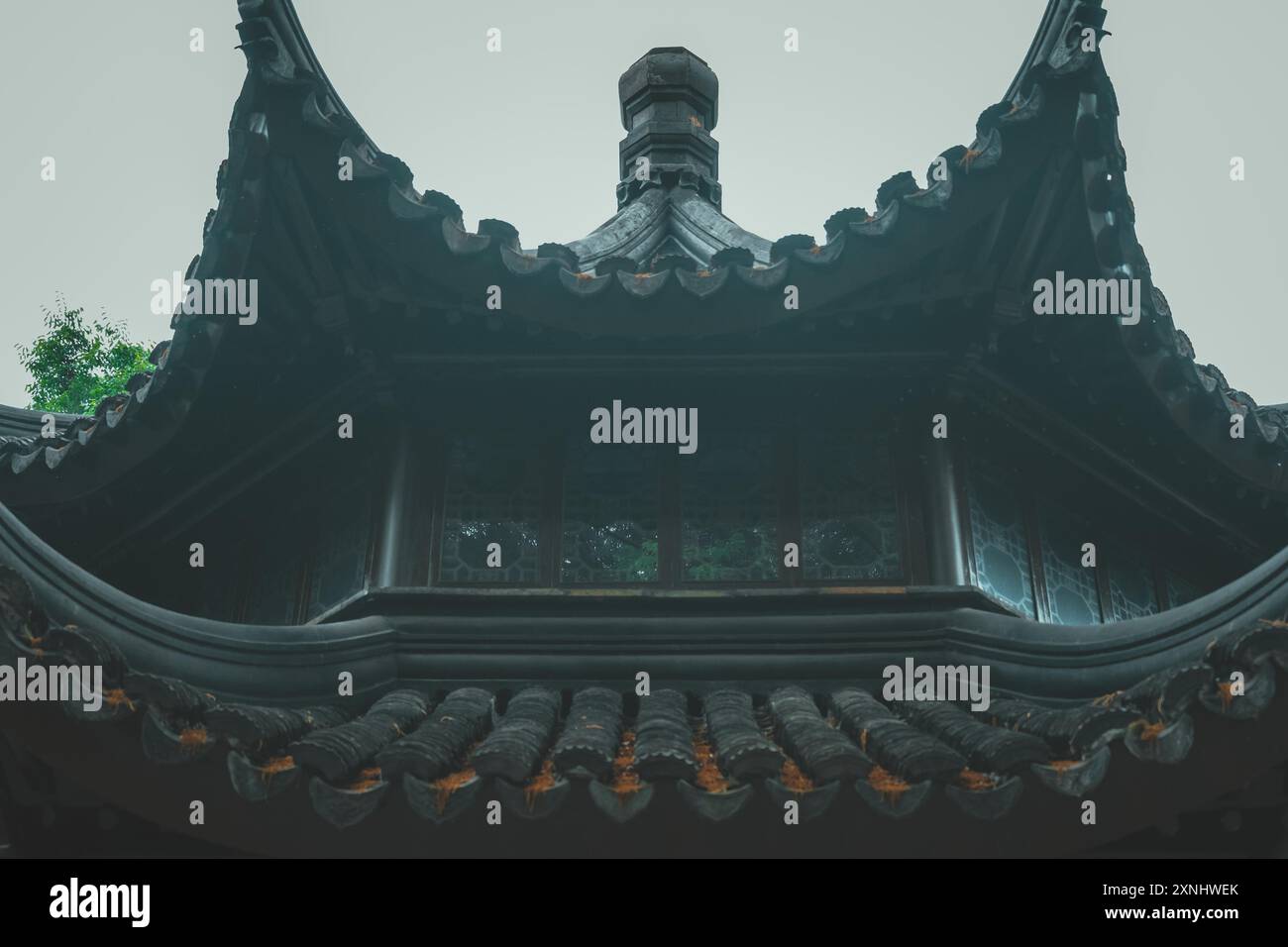 A low angle view of a traditional Chinese temple roof with intricate details and a window. Stock Photo
