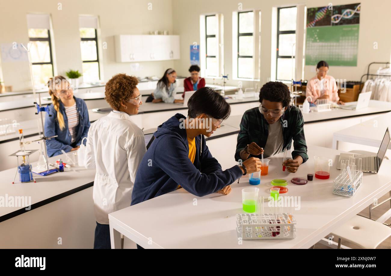 In high school, teenagers conducting science experiments in classroom laboratory setting Stock Photo