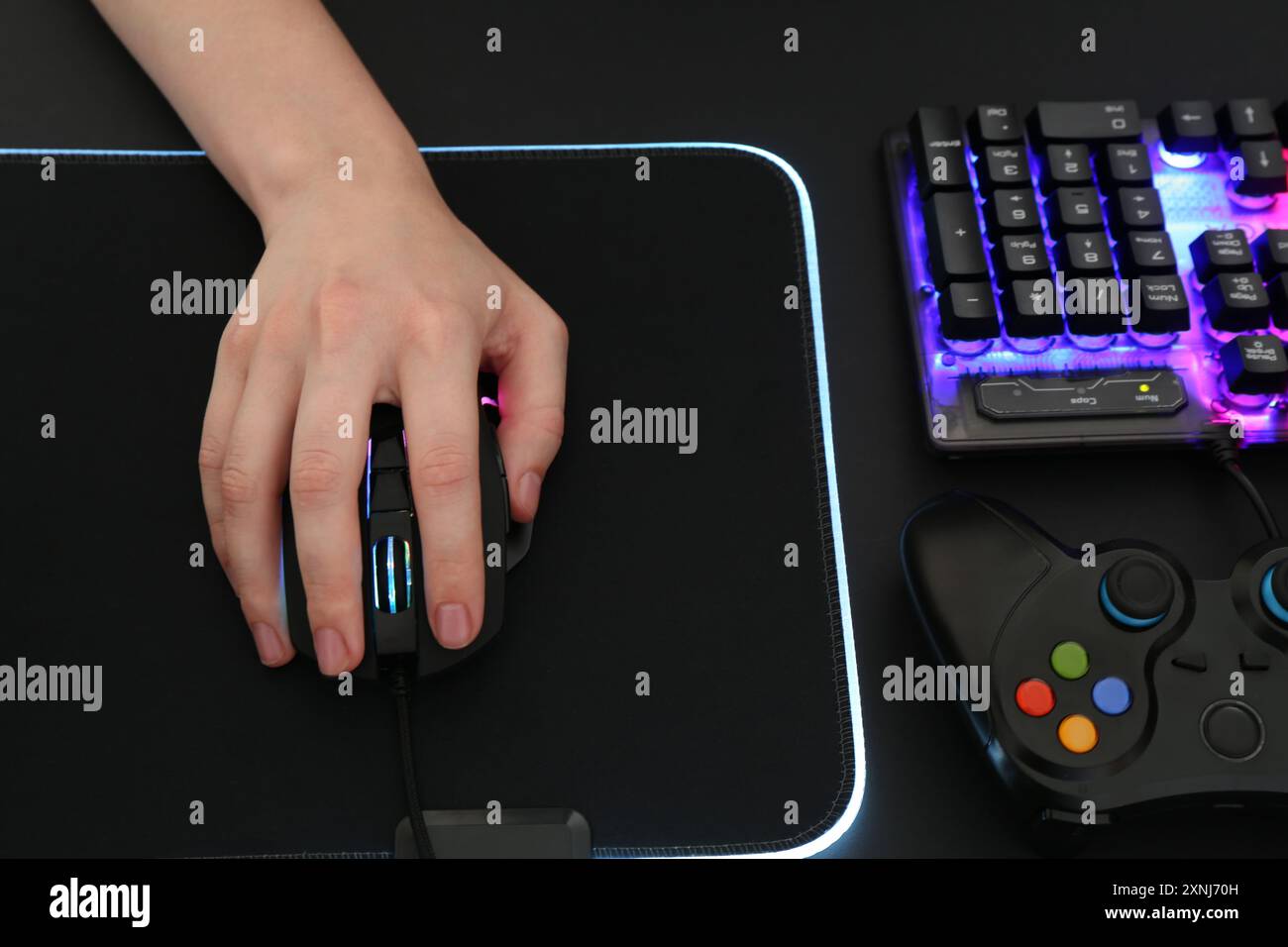Gamer using modern wired computer mouse at dark table, above view Stock Photo