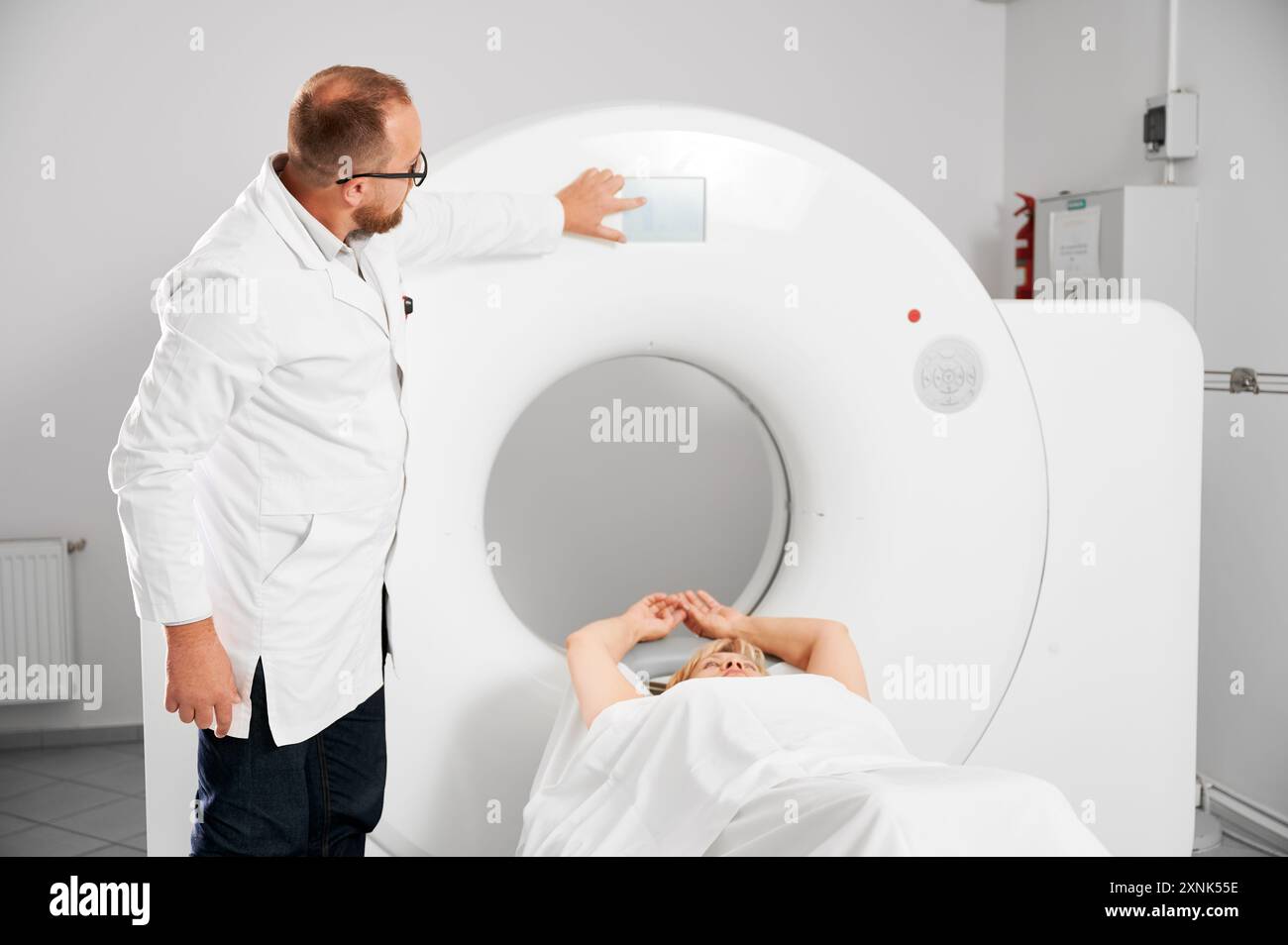 Medical computed tomography or MRI scanner. Male radiologist pointing ...