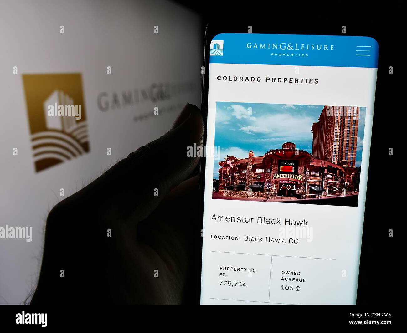 Person holding cellphone with webpage of US real estate company Gaming and Leisure Properties Inc. with logo. Focus on center of phone display. Stock Photo