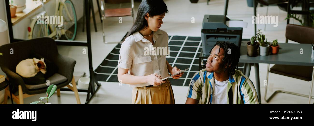 High angle view of gen Z Asian woman and Black man discussing business strategy at work in modern office, website header Stock Photo