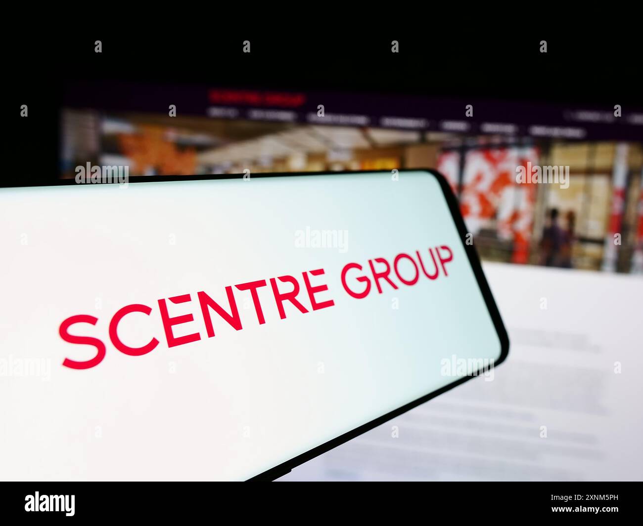 Cellphone with logo of Australian shopping center company Scentre Group Limited in front of website. Focus on center-left of phone display. Stock Photo