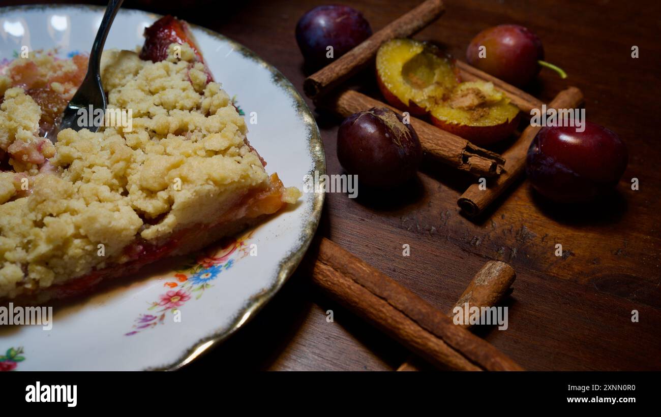 Homemade plum cake on a plate, a fork, plums, cinnamon. Stock Photo