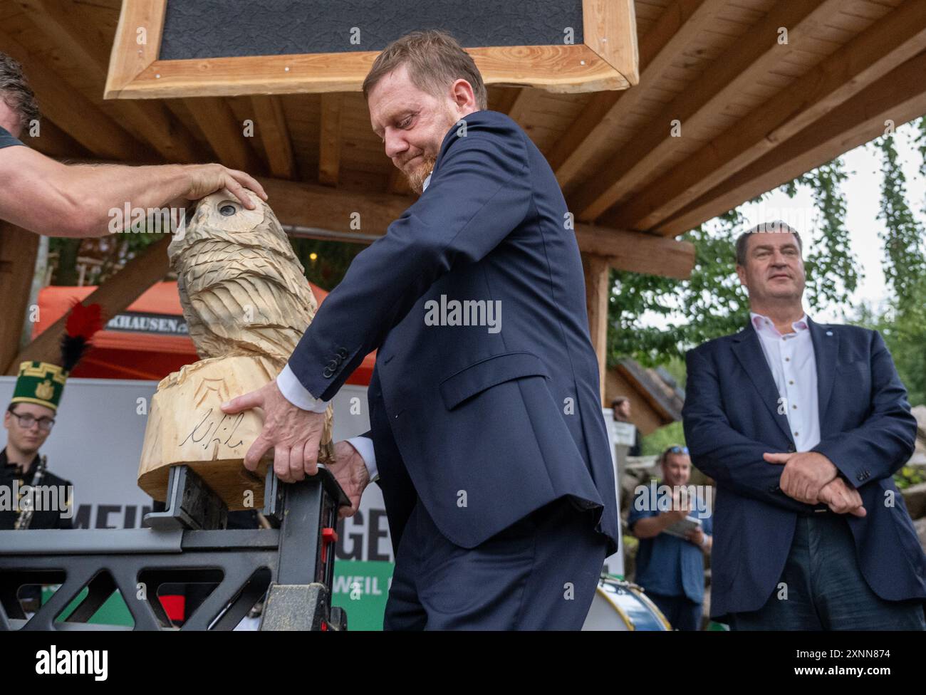 Dorfchemnitz, Germany. 01st Aug, 2024. Michael Kretschmer (CDU, l), Minister President of Saxony, lifts a wooden owl figure from a trestle next to Markus Söder (CSU), Minister President of Bavaria, at a CDU Saxony election campaign event in Dorfchemnitz. The Minister Presidents want to talk to the regional CDU direct candidates and visitors on site. Credit: Hendrik Schmidt/dpa/Alamy Live News Stock Photo