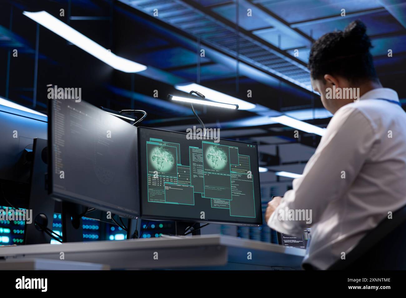 Software developer using computer in server room to support global connections using their hardware. IT expert inspecting data center hardware supporting worldwide network using PC Stock Photo