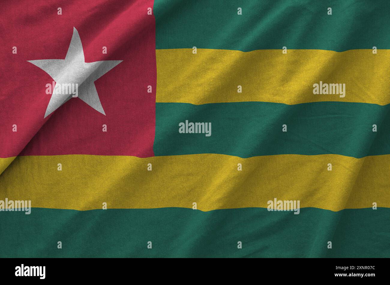 Togo flag depicted on folded wavy fabric of old cloth close up Stock Photo