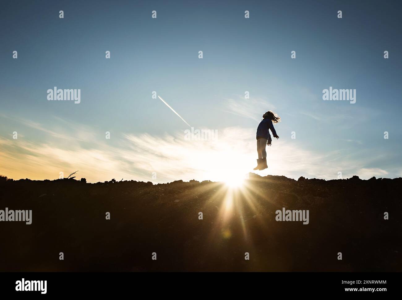 Young girl jumping against sunburst and blue sky Stock Photo - Alamy