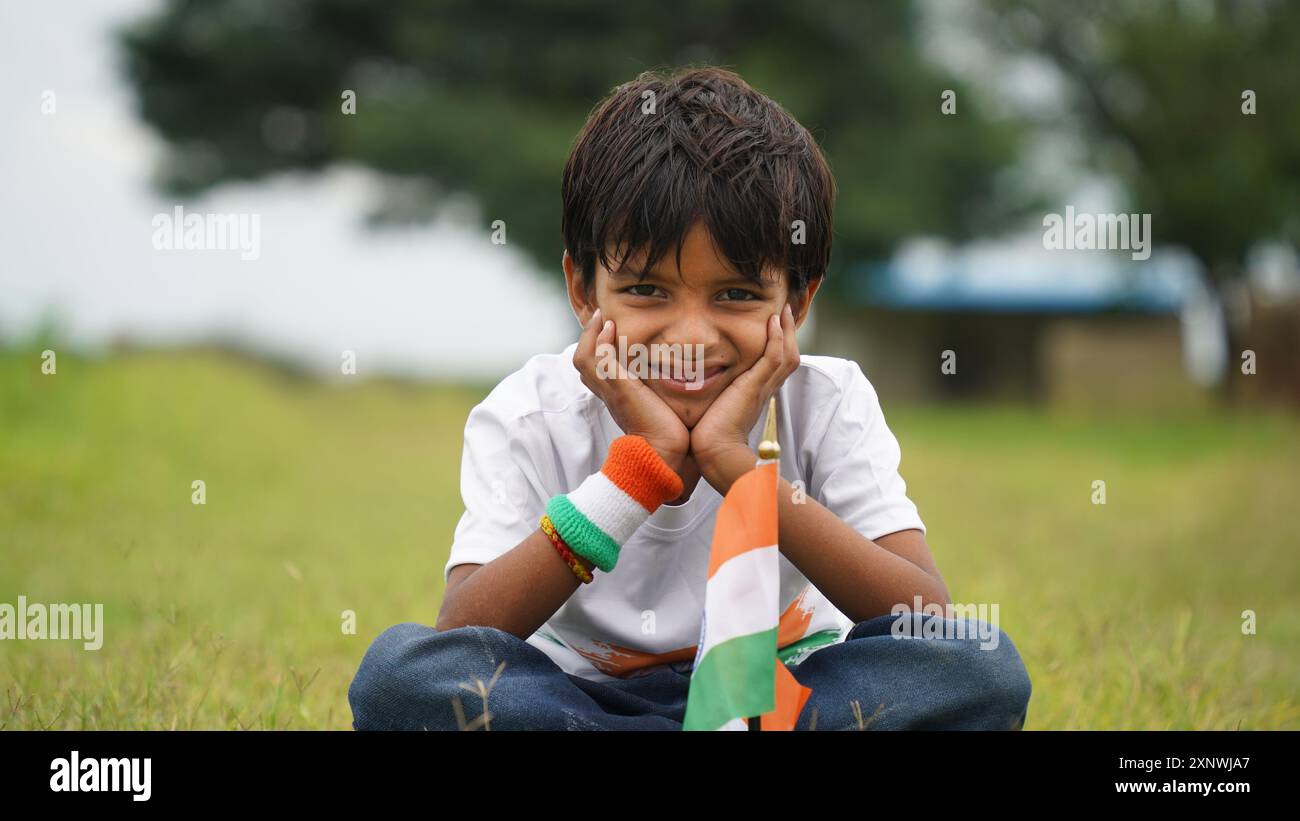 Happy Indian Cute Smiling little boy waving tricolor flag at outdoor park, celebrating Independence day or Republic day. Stock Photo