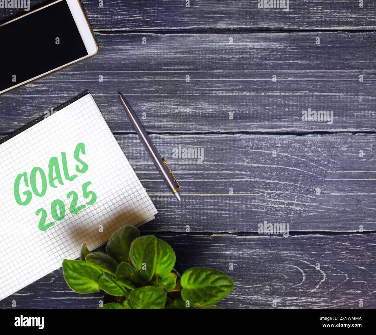 Notes with words Goals 2025 and pen with phone. Motivation, inspiration