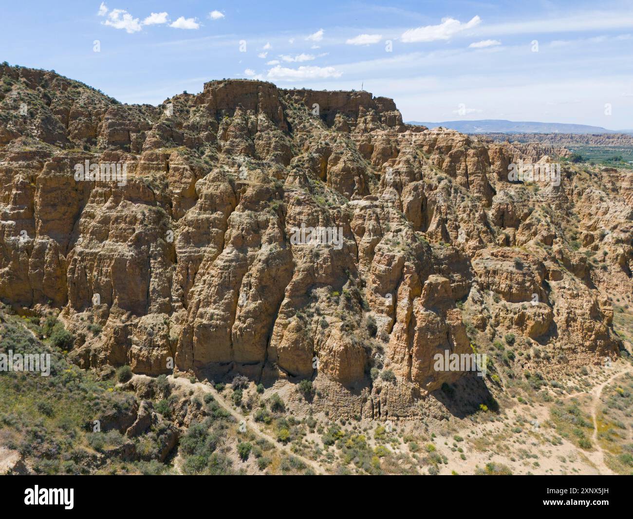 A rocky and hilly area with cliffs under a clear blue sky, aerial view ...