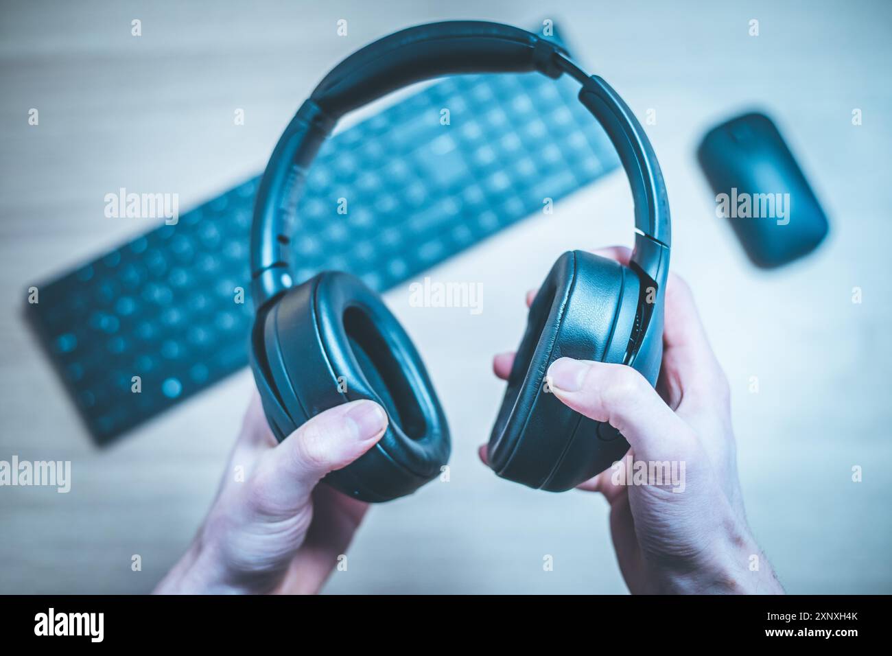 Male hands are holding black wireless headphones, workspace Stock Photo