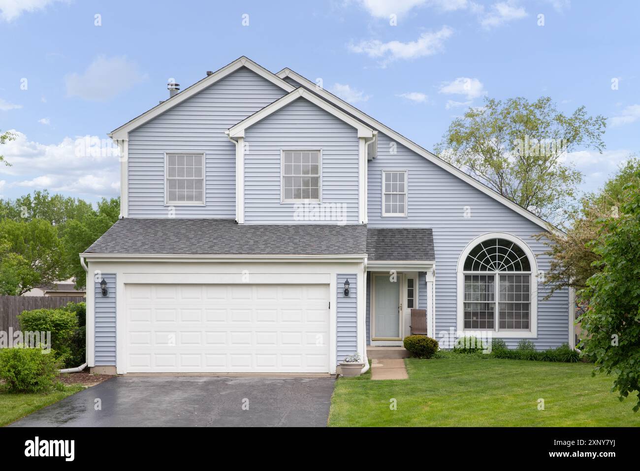 A two story suburban home with light blue siding and white trim, a ...