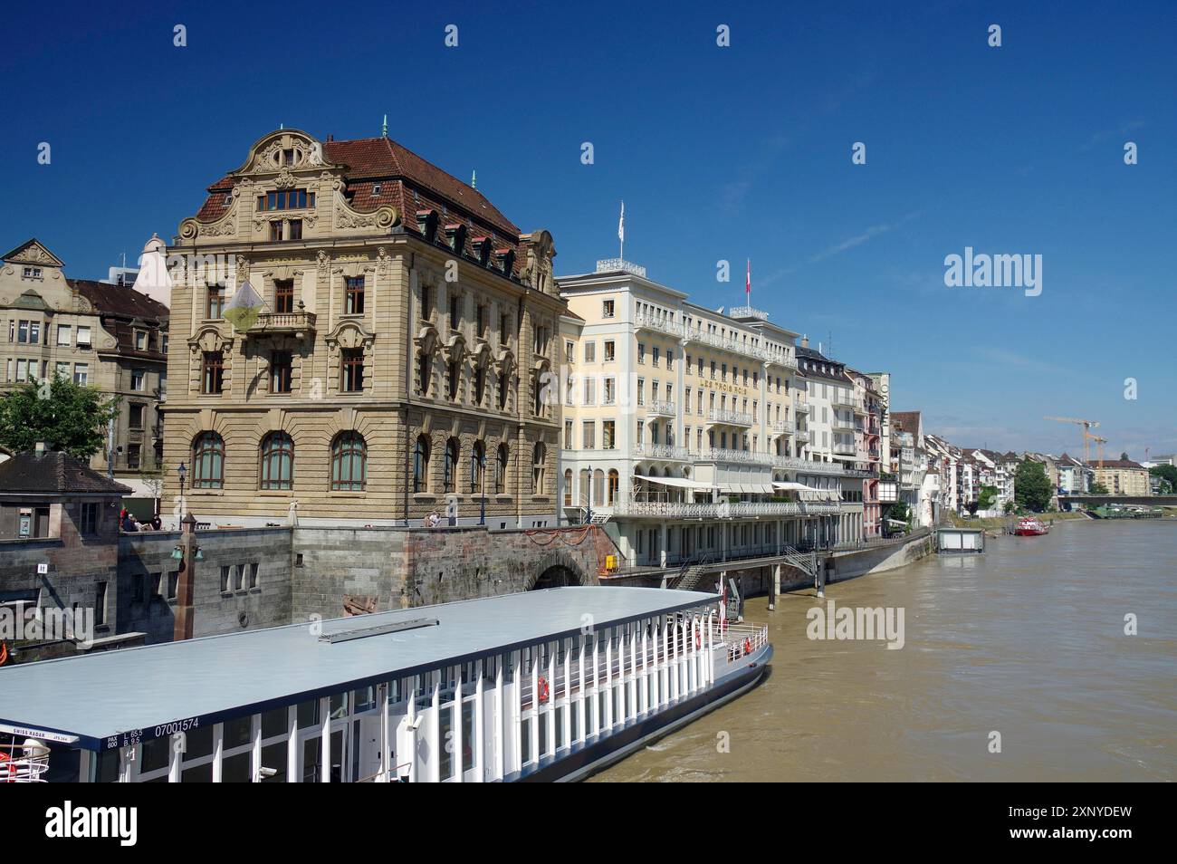 Elegant riverside buildings with small cruise ships under a bright blue ...