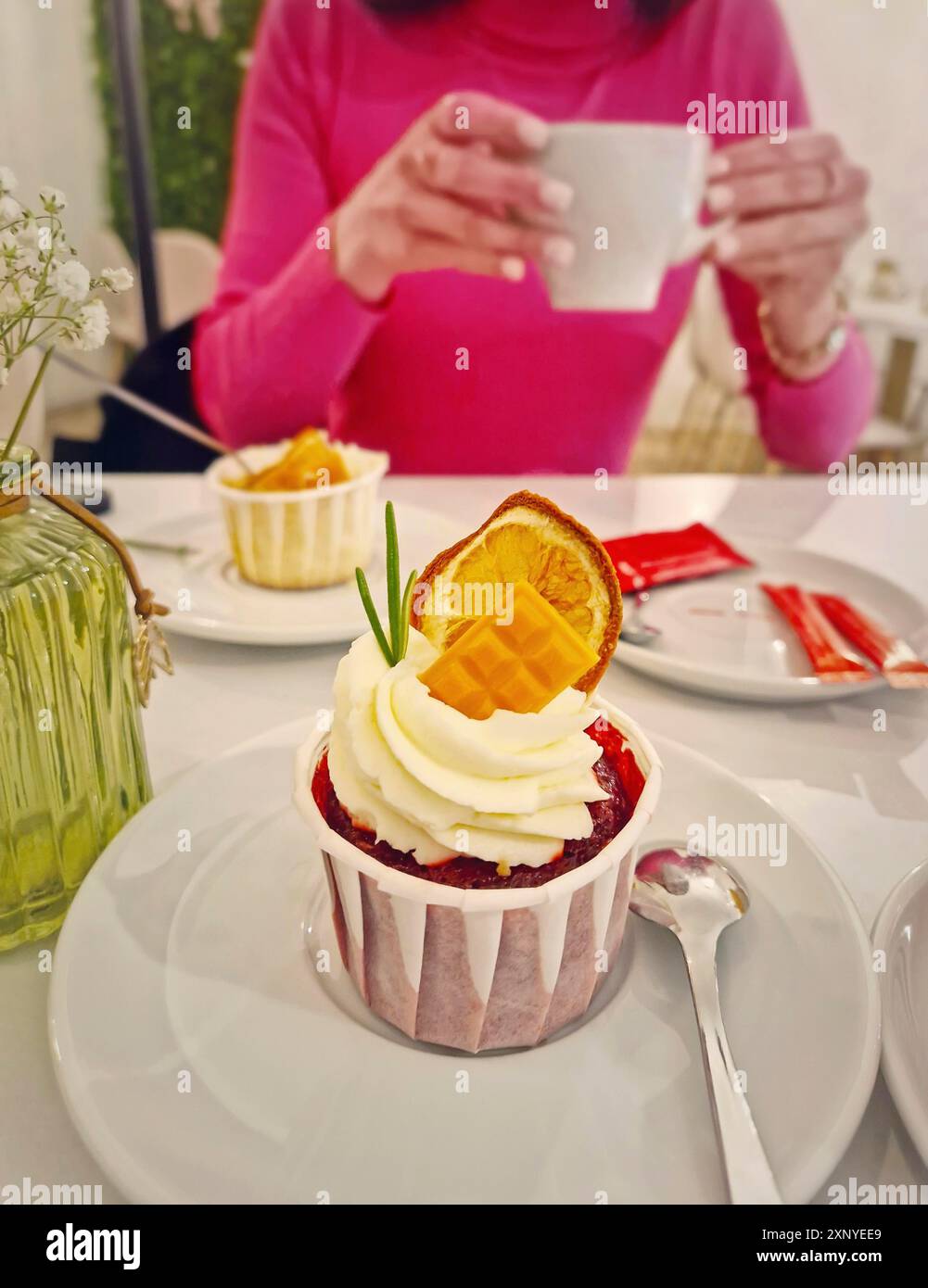 Aesthetics view with a carefree young woman in a cafe enjoys a cup of tea with cupcake Stock Photo