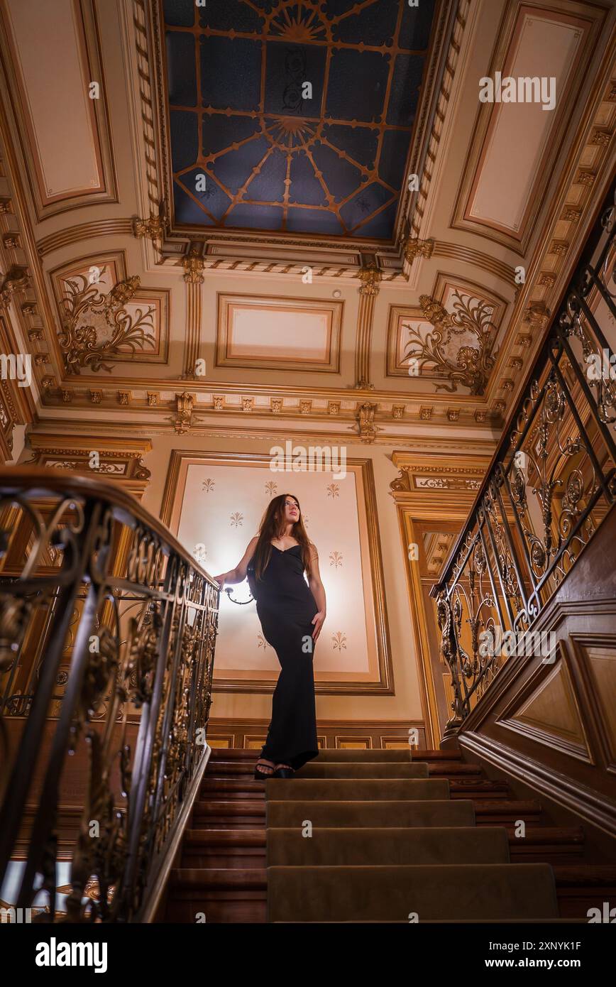 Elegant Woman in Black Evening Gown on Grand Staircase with Gold ...