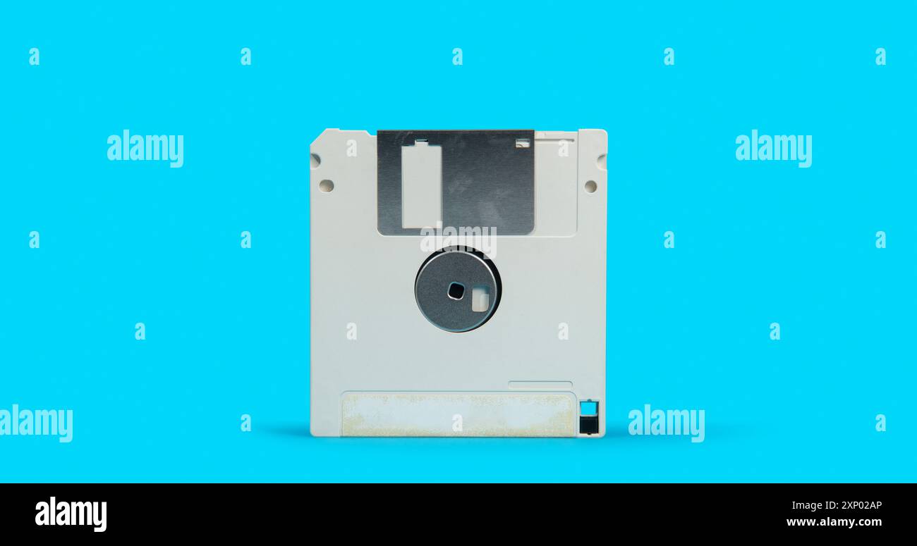 Front view of old white plastic square computer floppy disk on a blue ...